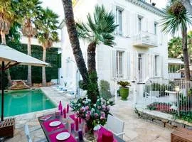 Villa Roses d'Antibes: looking across the terrace from a table set with 4 places to the front of this pretty art deco house with the pool and sun loungers to the left.