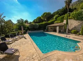 A large pool set into a private stone terrace with 4 beach loungers on the left nestles into the surrounding lush green landscape.